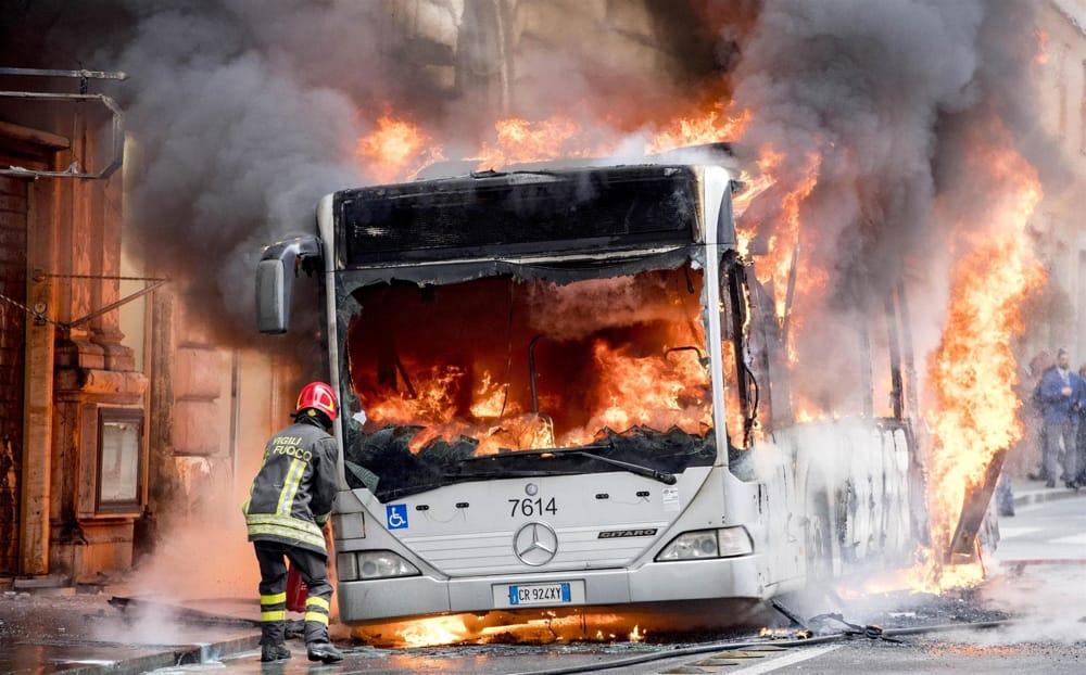 Un pompiere intento a spegnere le fiamme di un bus che ha preso fuoco in pieno centro di Roma