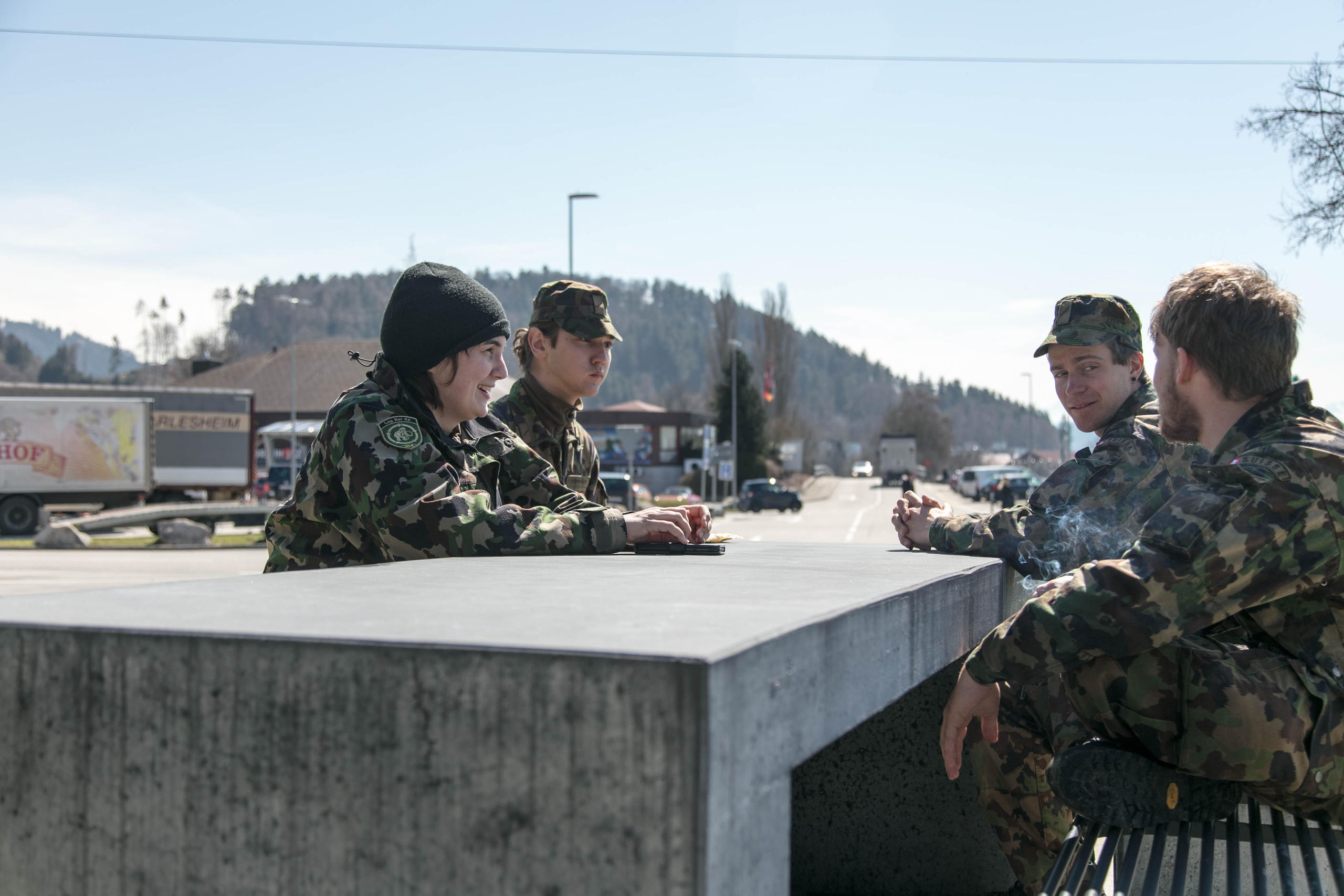 quattro soldati seduti a un tavolo di cemento in una stazione di servizio