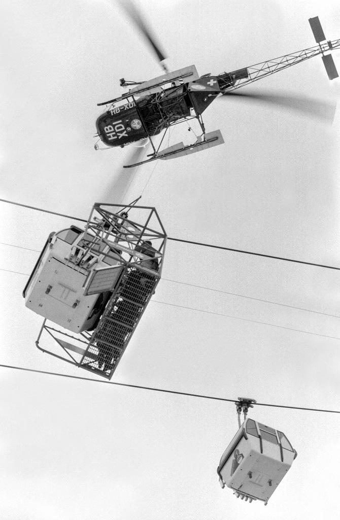 A helicopter flies above a cable car