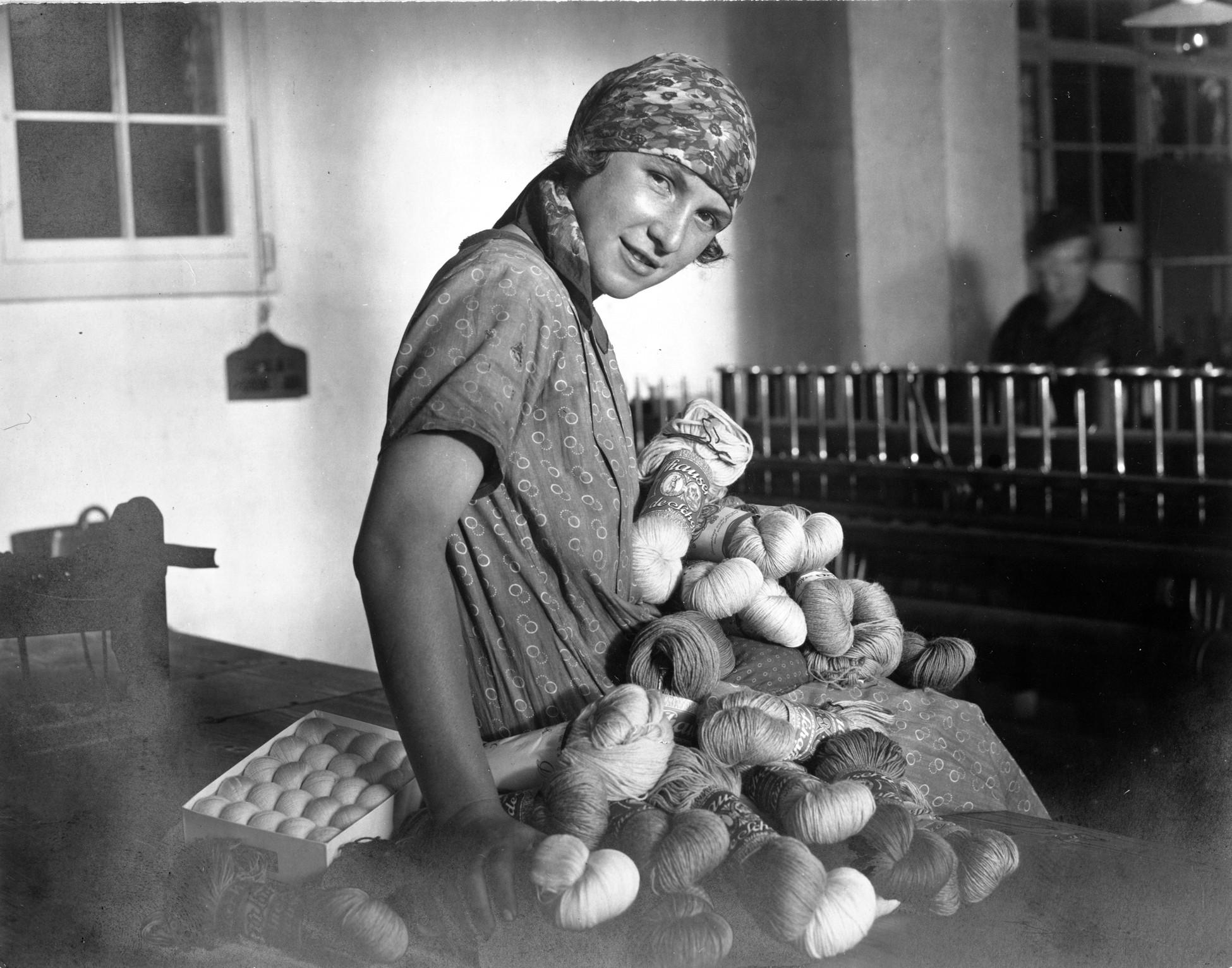 Black and white image of a woman holding balls of wool