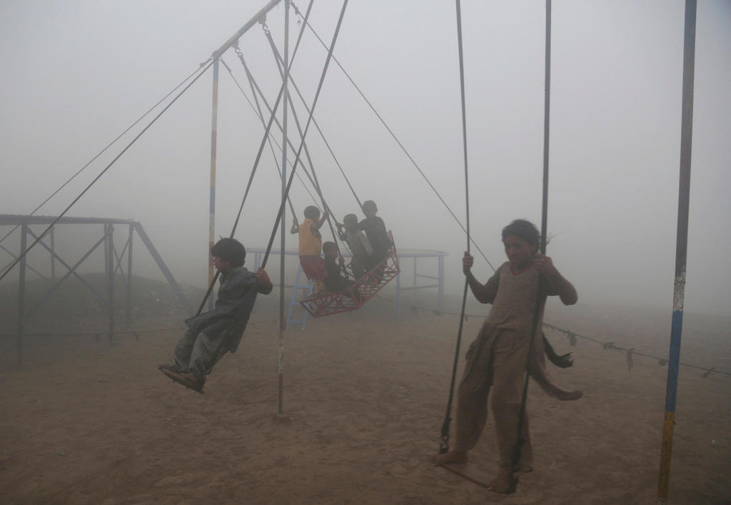 bambini giocano su un altalena a Lahore, in Pakistan. L aria è totalmente grigia a causa dello smog