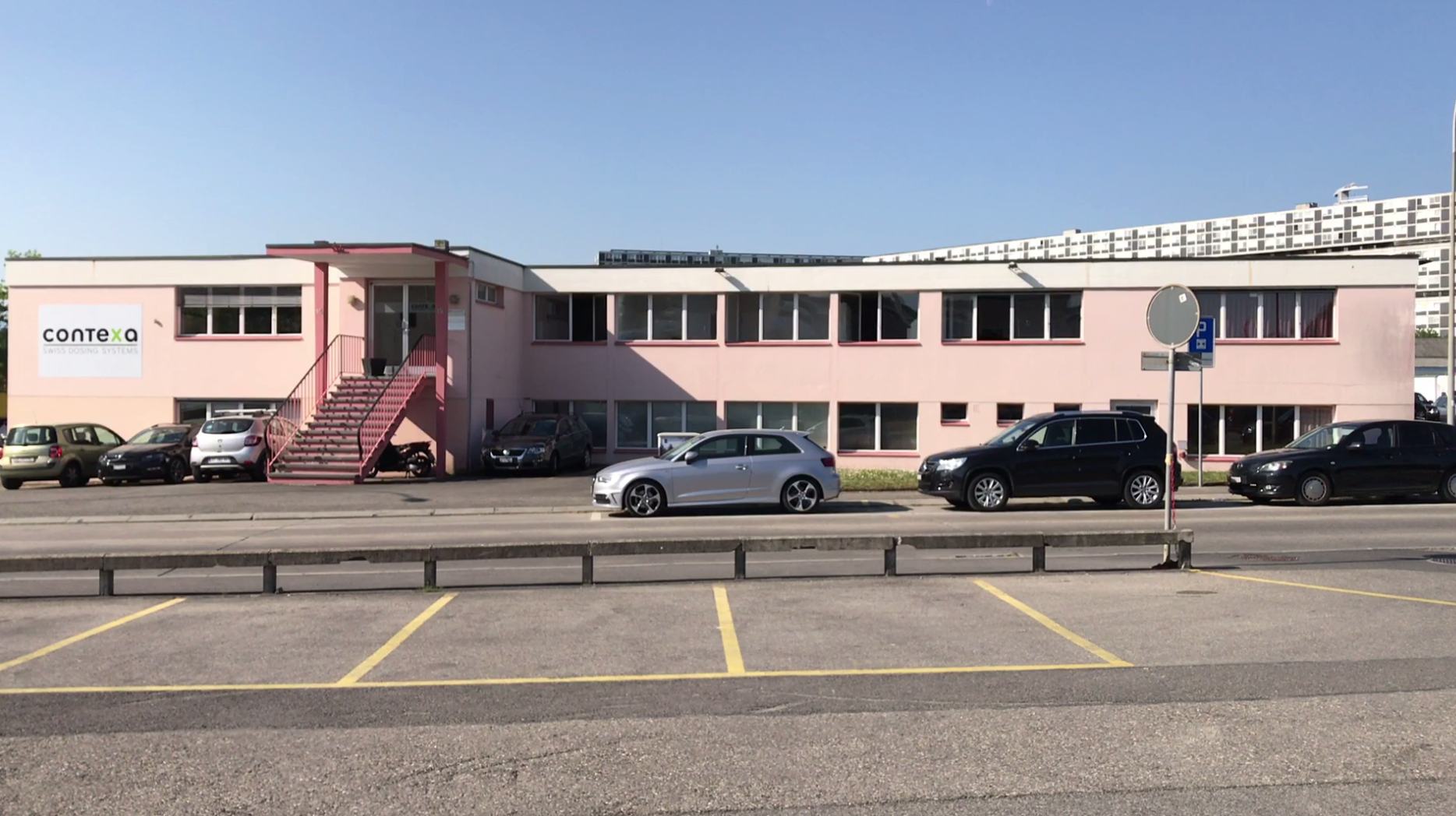 auto parcheggiate davanti a un edificio di due piani e di colore rosa