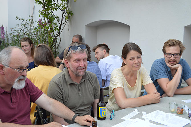 Menschen sitzen bei Bier an Tischen