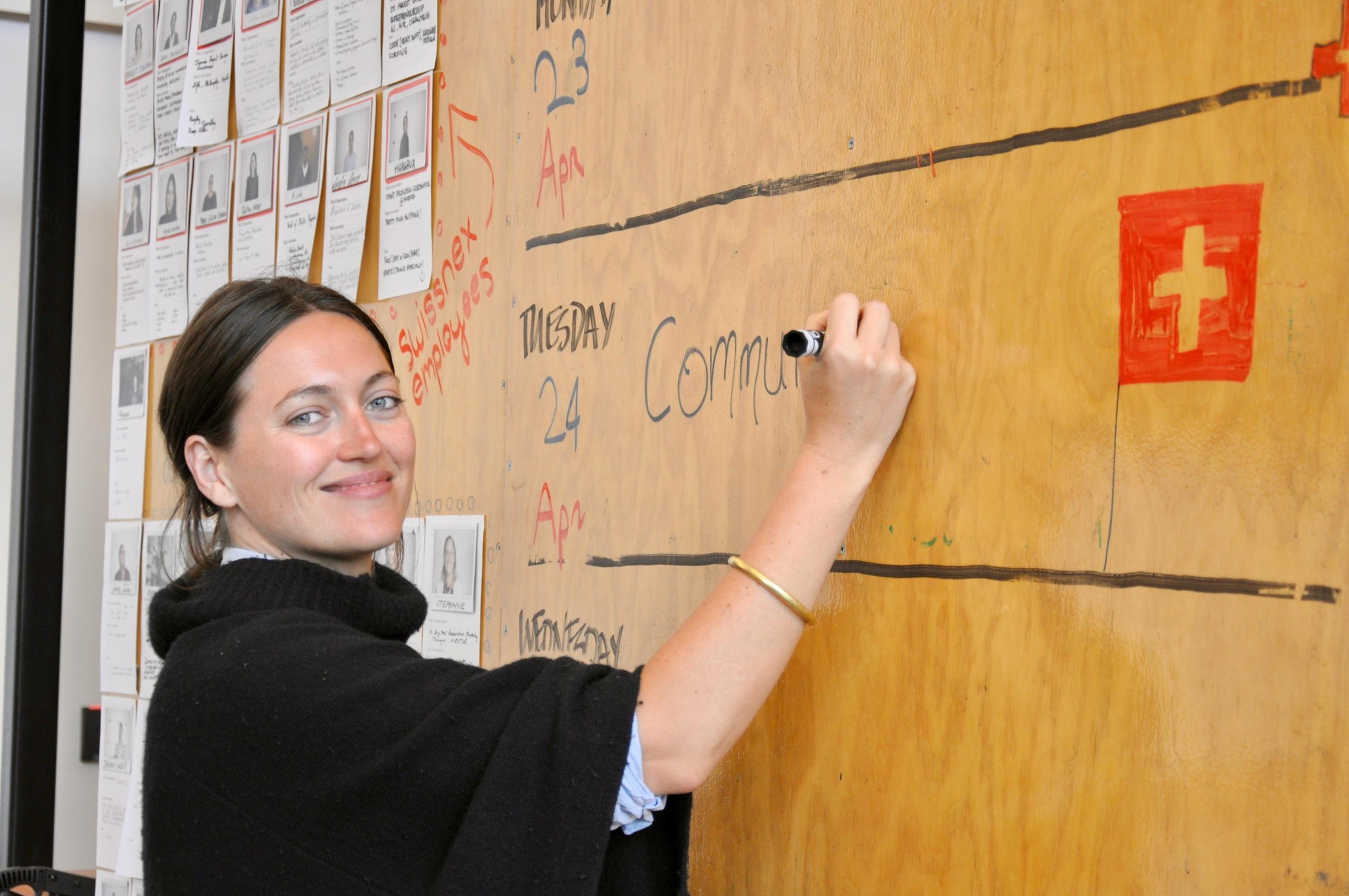 Perrine Huber von Swissnex schreibt an einer Infotafel aus Holz das Wort Community