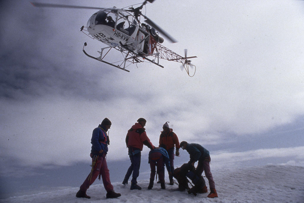 Un helicóptero desciende en dirección de un grupo de personas.