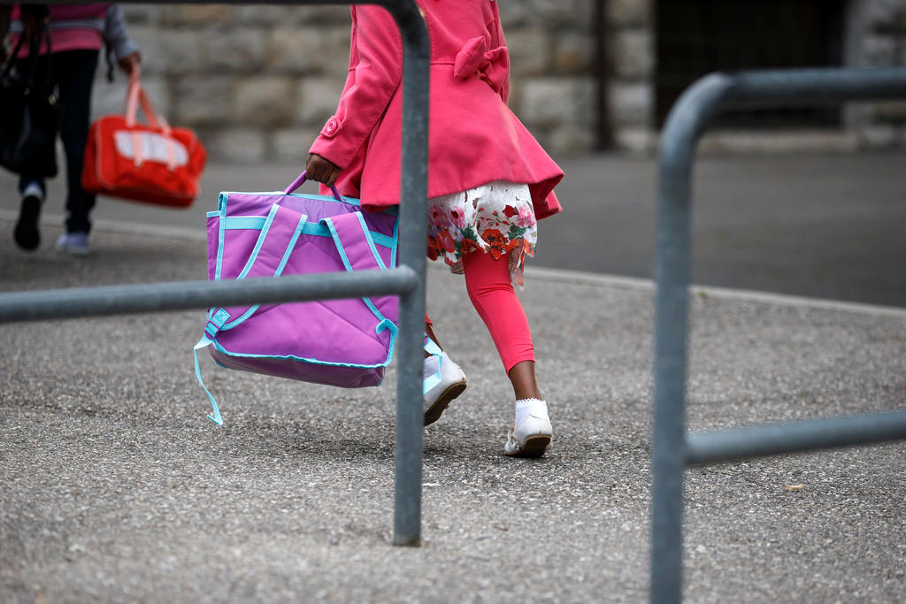 Child carrying backpack on way to school.