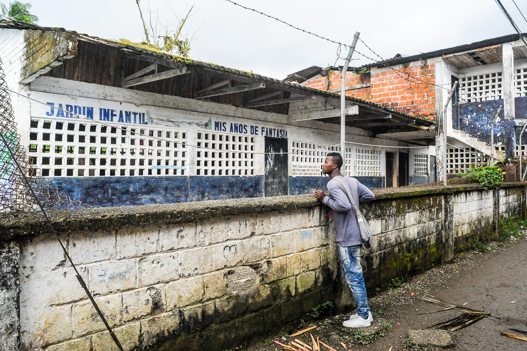 A man looking over a wall to a building with white walls