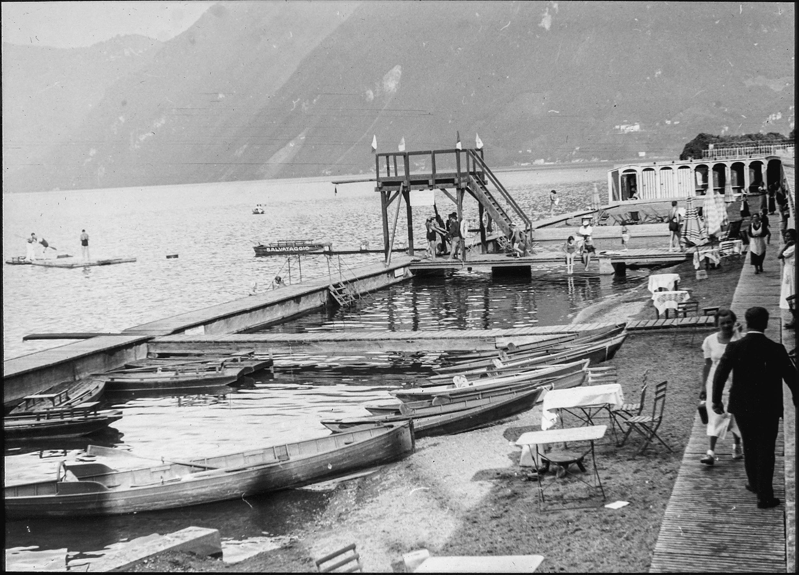 boots and people on the boardwalk along a narrow beach