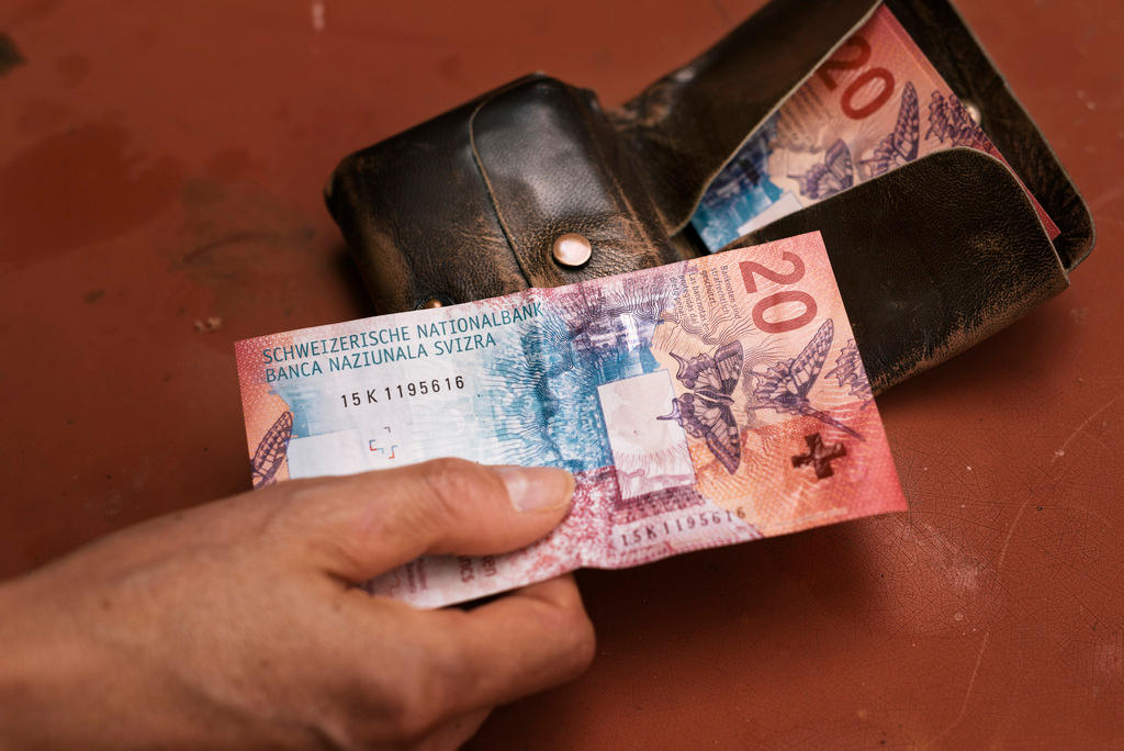 A man holds a 20 Swiss Francs bill in his hand