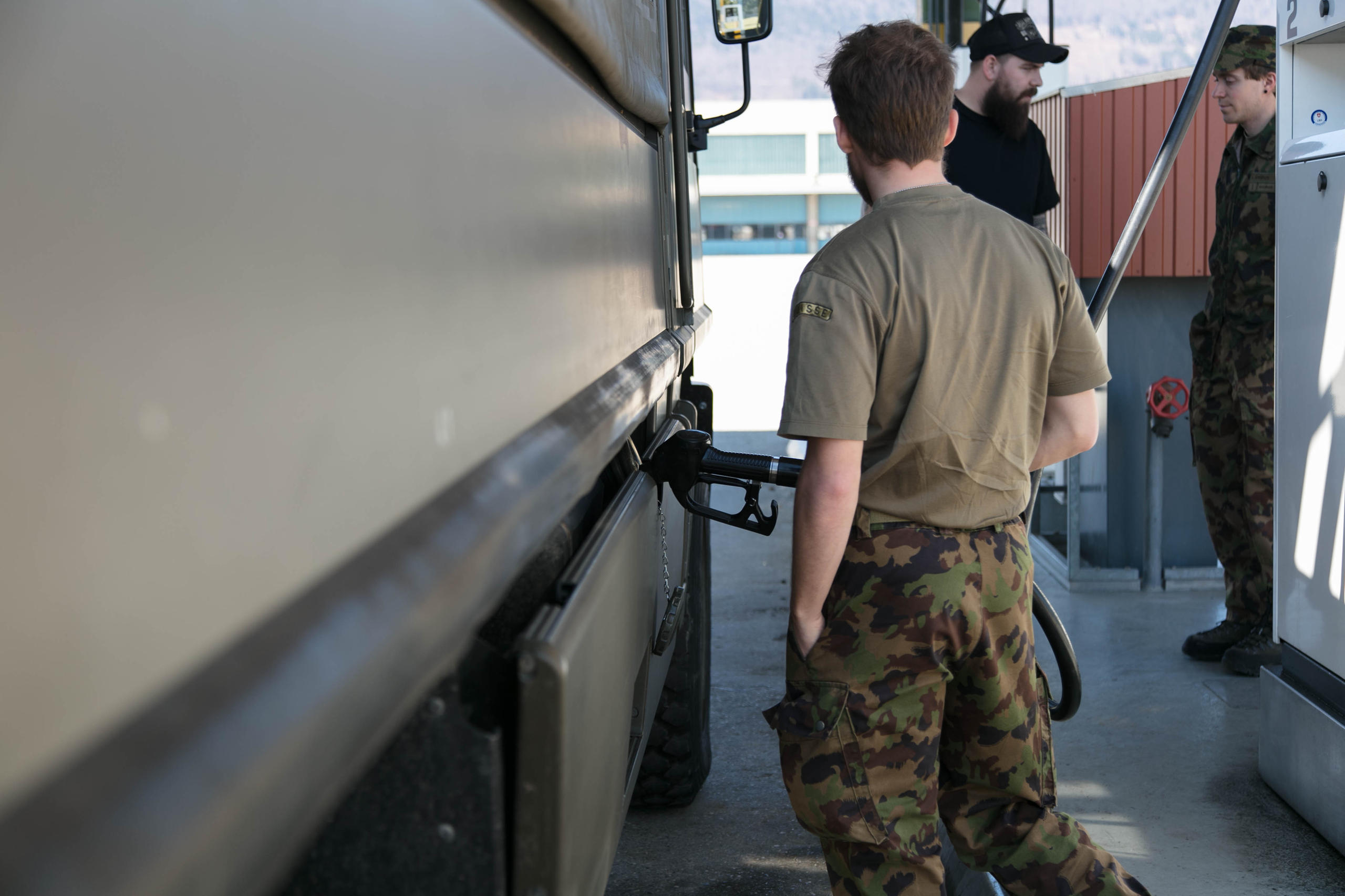 un soldato fa il pieno di benzina a un veicolo militare