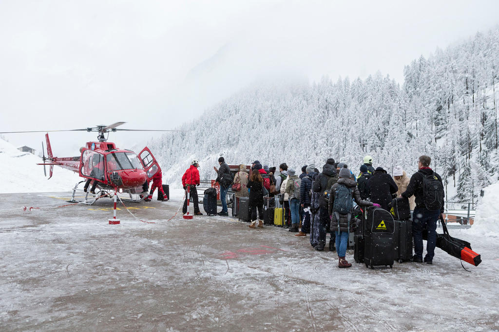A queue of people stand near to a helicopter