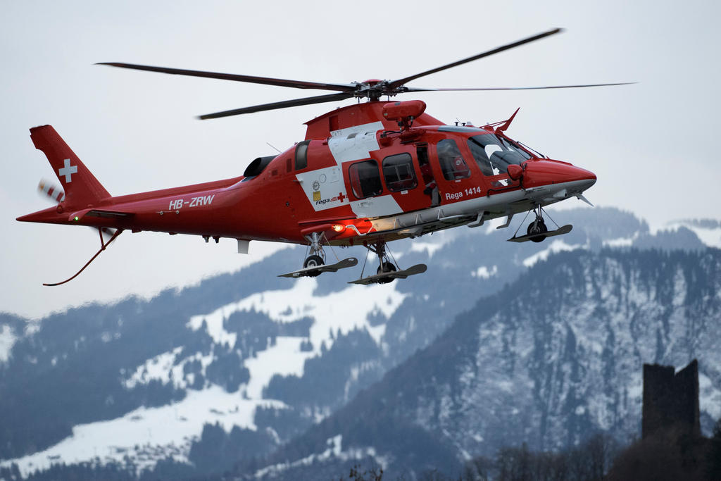 A red helicopter flies in the mountains
