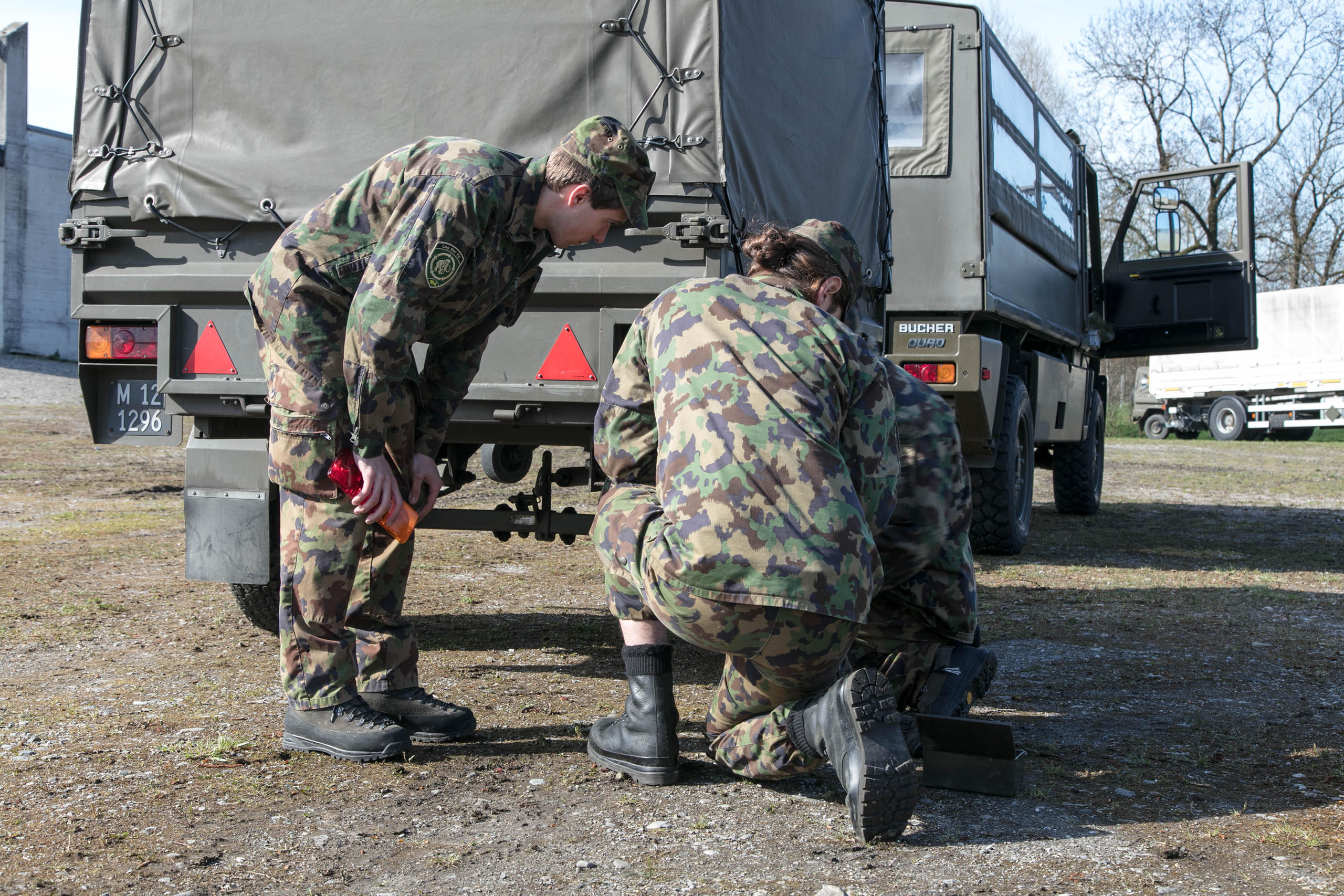 tre soldati sono inginocchiati dietro a un veicolo militare