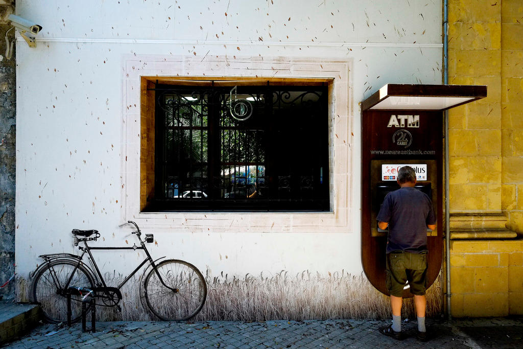 A man uses the ATM outside a bank in Cyprus.