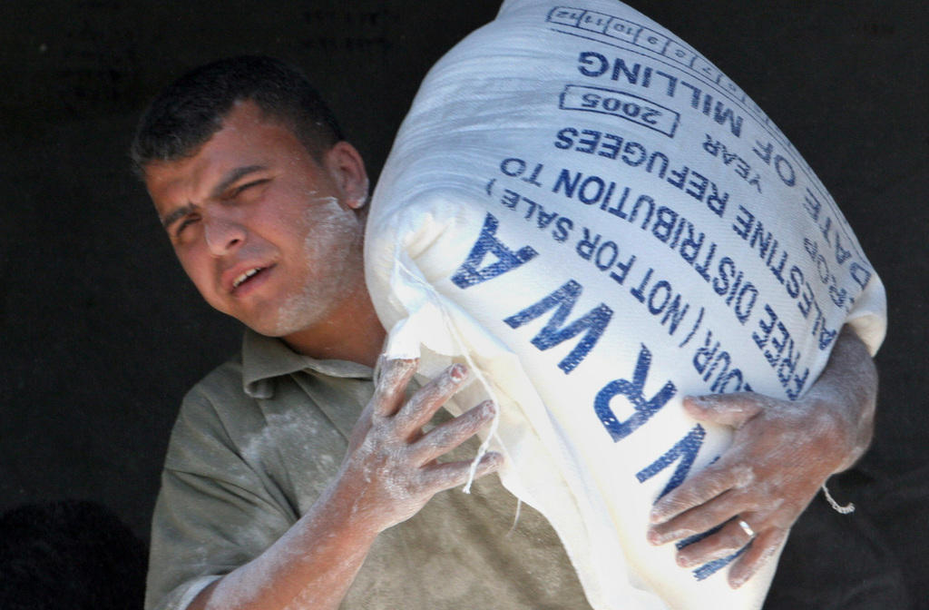 عامل فلسطيني يحمل كيسا من الطحين من الأونروا