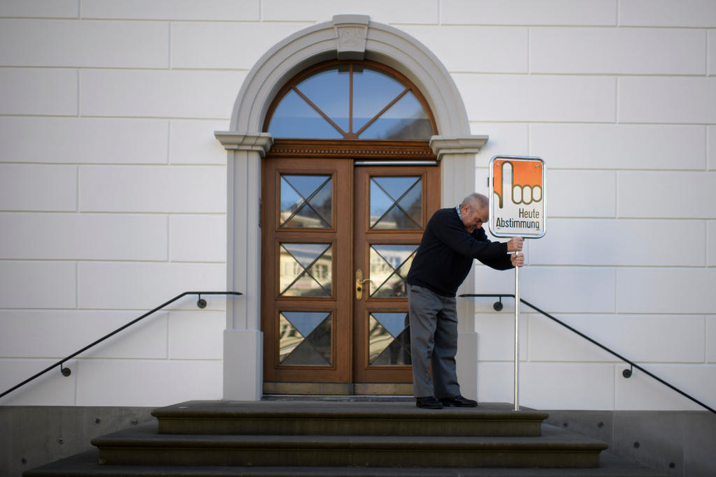 Ein Mann stellt ein Schild auf. Darauf steht: Heute Abstimmung