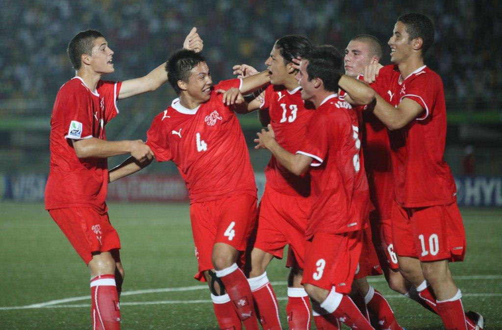 Sei giocatori della nazionale svizzera Under 17 si stanno abbracciando in mezzo al campo.