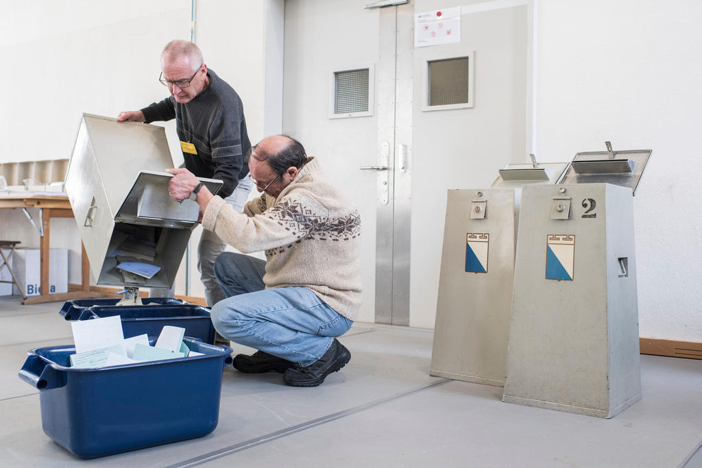 Two men empty vote papers from a ballot box