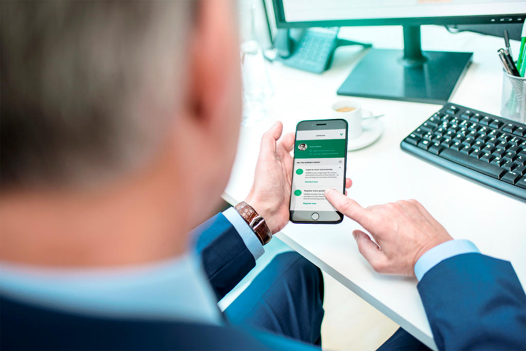 Man using a mobile phone next to his desktop computer