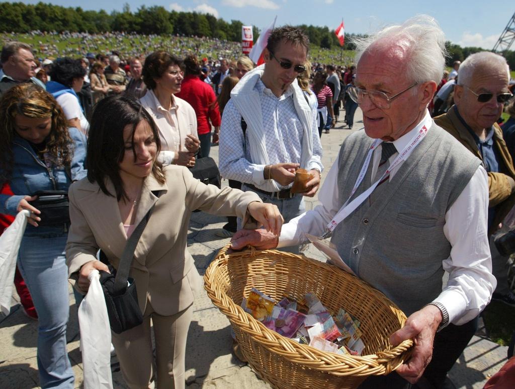 2004年6月6日，一名执事在伯尔尼的户外弥撒中收集信徒的奉献款。