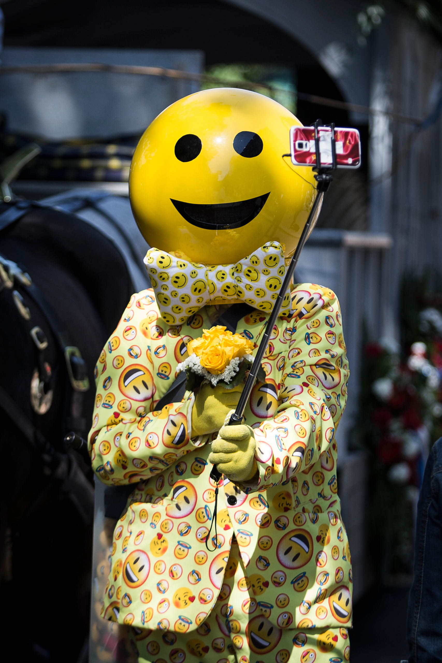 رجل يرتدي ملابس عليها صور ابتسامات ويحمل هاتفا ذكيا ويلتقط صورة سلفي لنفسه