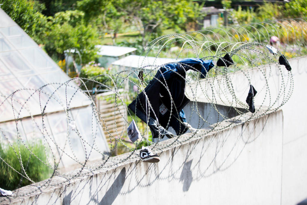 Clothes hang in the barbed wire fence of a reception and procedure centre for asylum seekers.