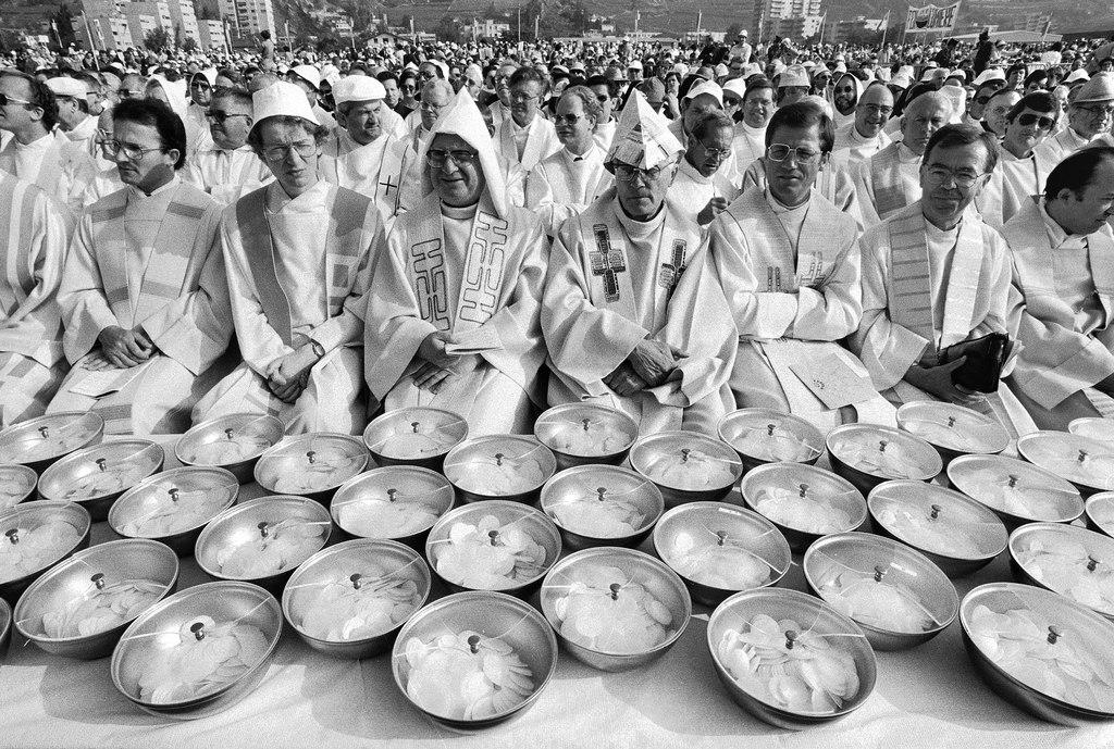 people wearing white robes kneeling behind many containers with lids