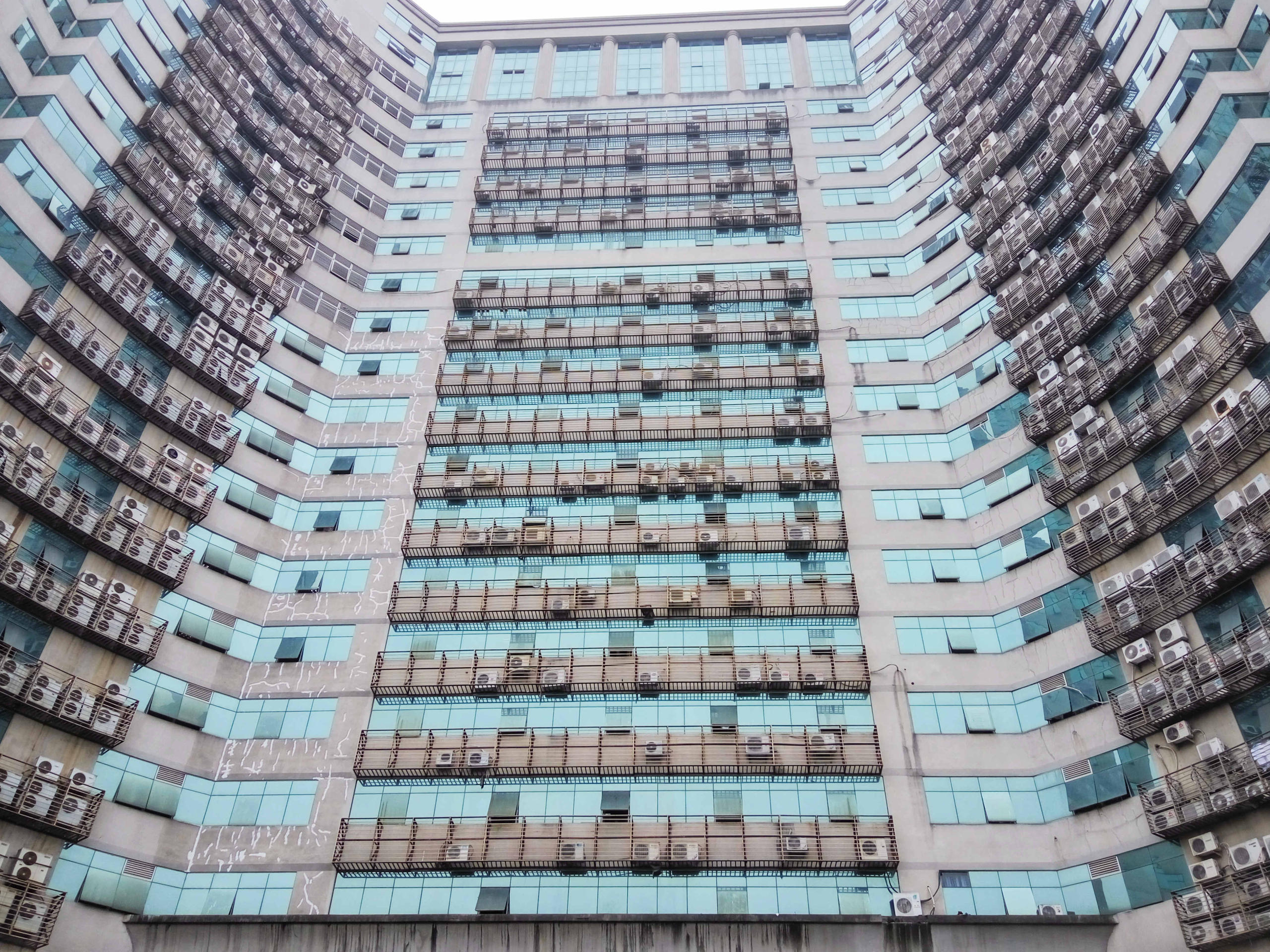 الجزء السفلي لعمارة شاهقة في الصين ومكيفات الهواء في كل الشقق