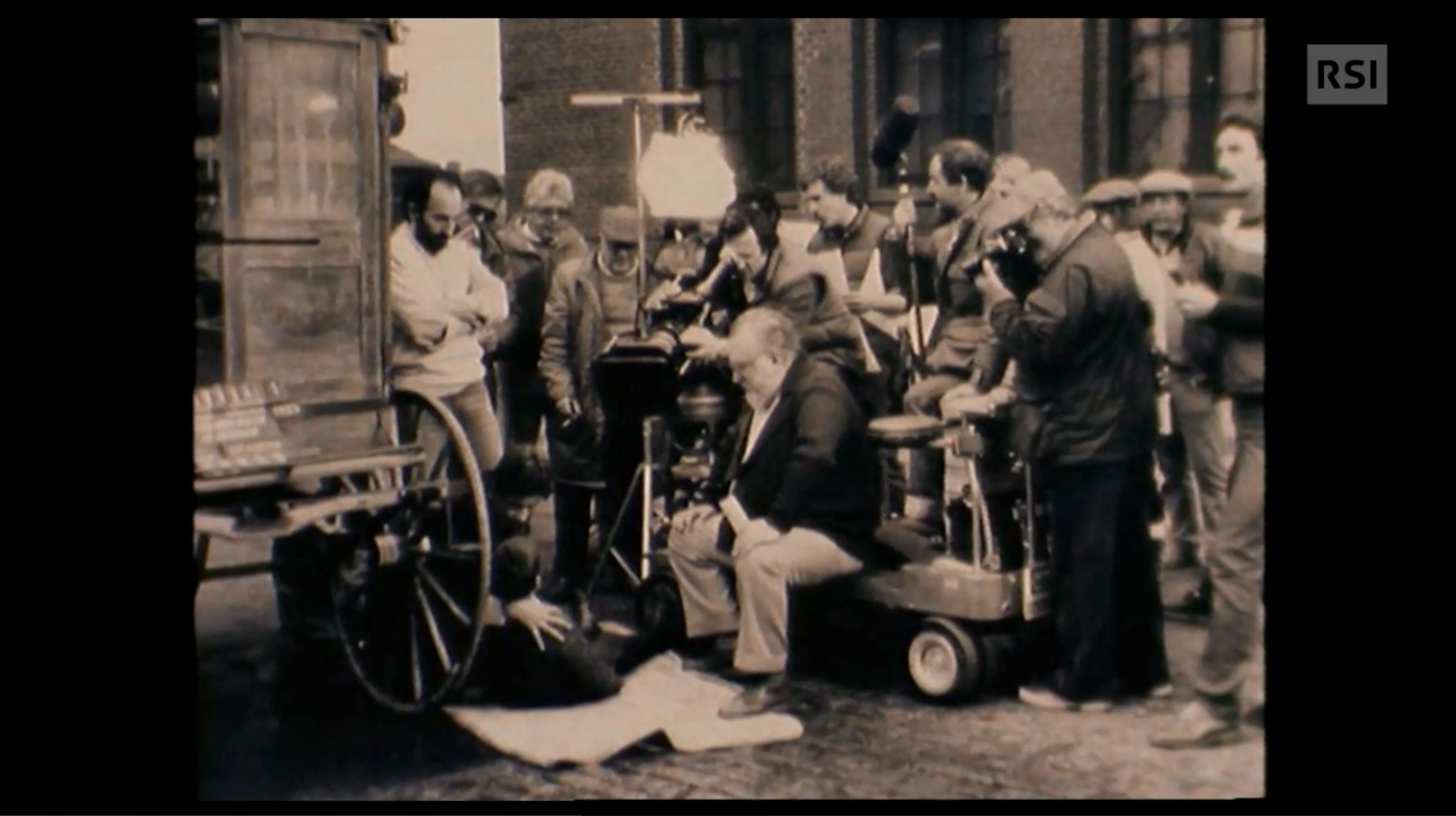 Sergio Leone e il suo cineoperatore filmano una scena che si svolge sul fondo stradale accanto alla ruota di un carro