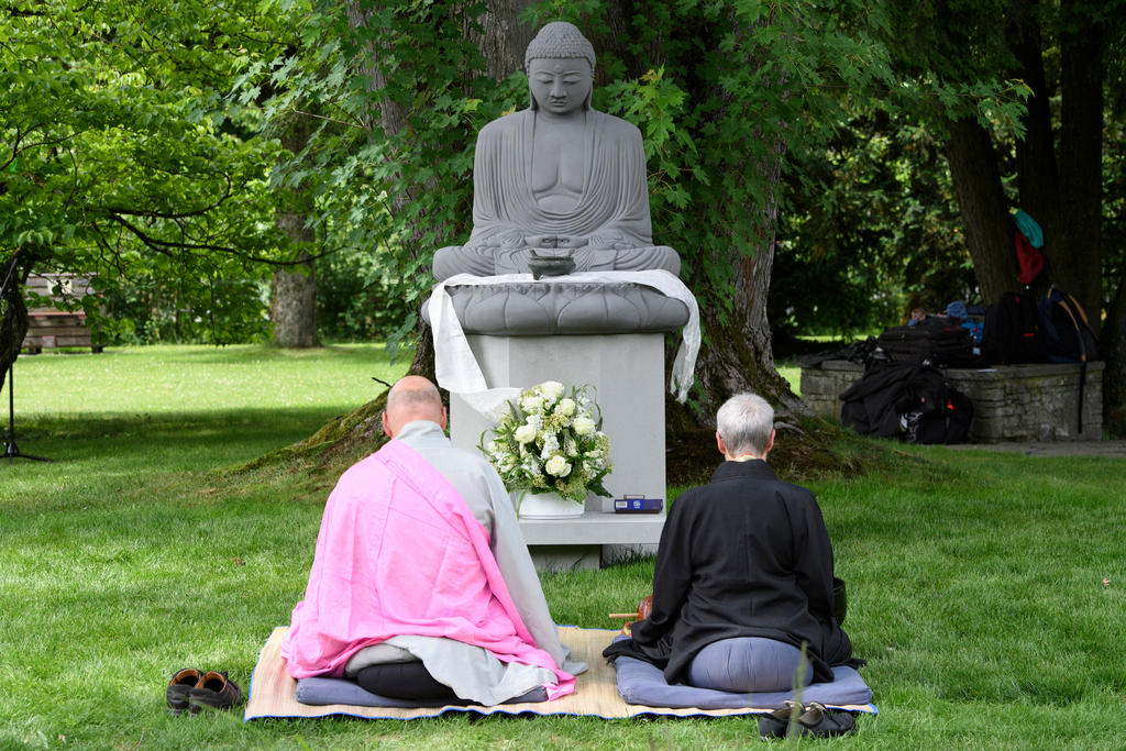 رجل وامرأة يجلسان أمام تمثال لبوذا في حديقة