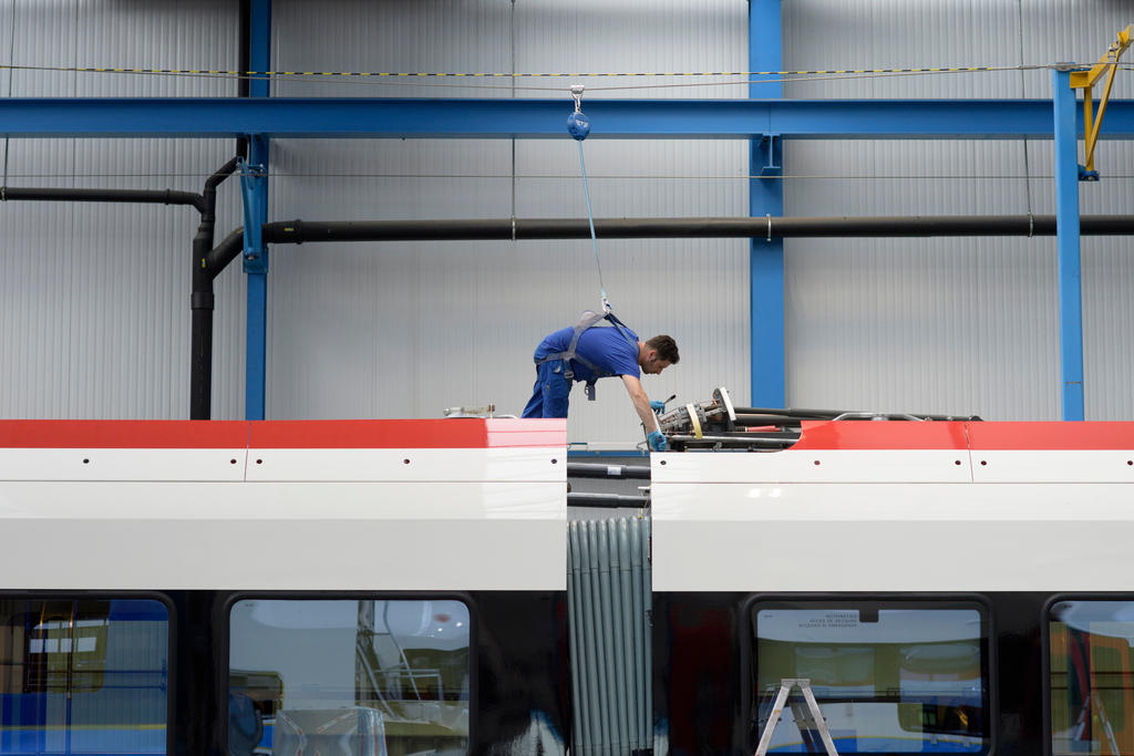 Ein Arbeiter hängt an Sicherheitsgurten über dem Dach eines Eisenbahnwagens