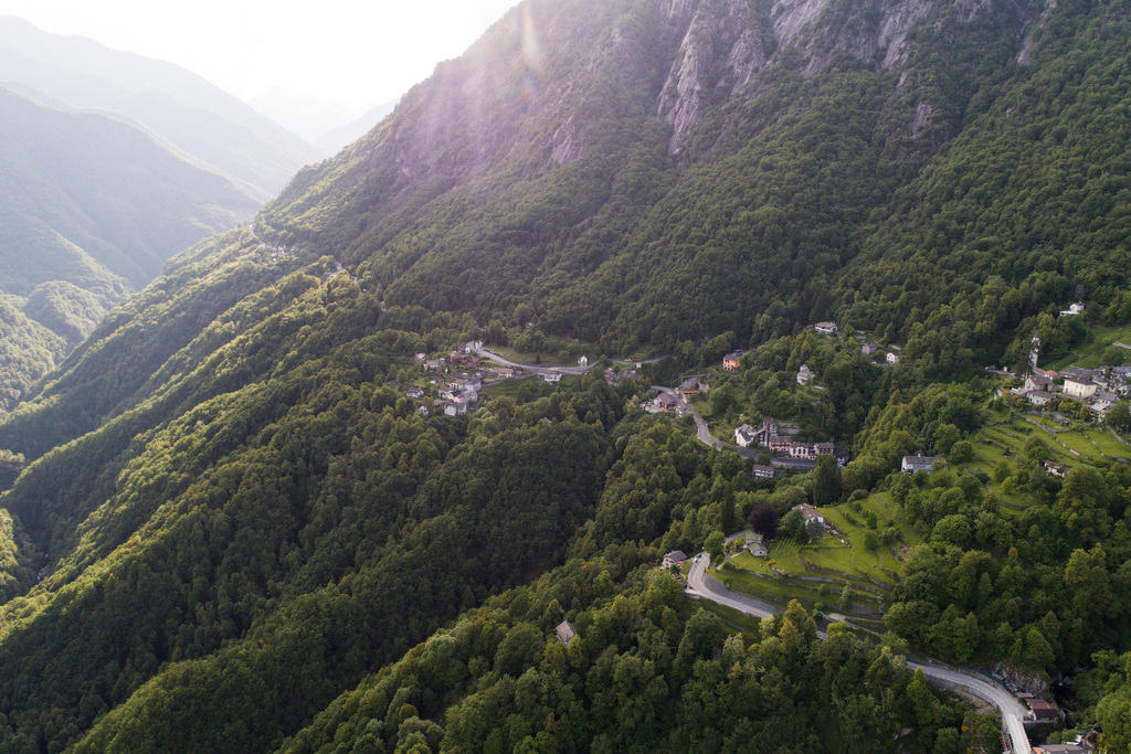 Paesaggio della Val Onsernone, con boschi, alcune case e una strada sul finaco dlela montagna