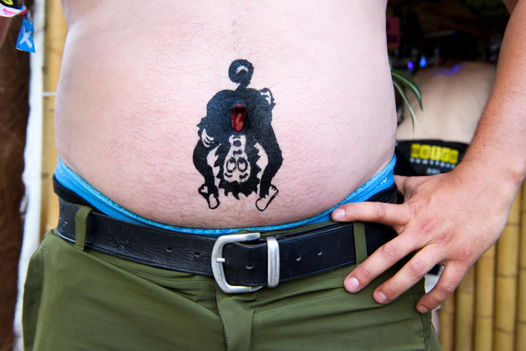 Pancia di un uomo sulla quale è tatuata una scimmia piegata che cerca di guardarsi il sedere.