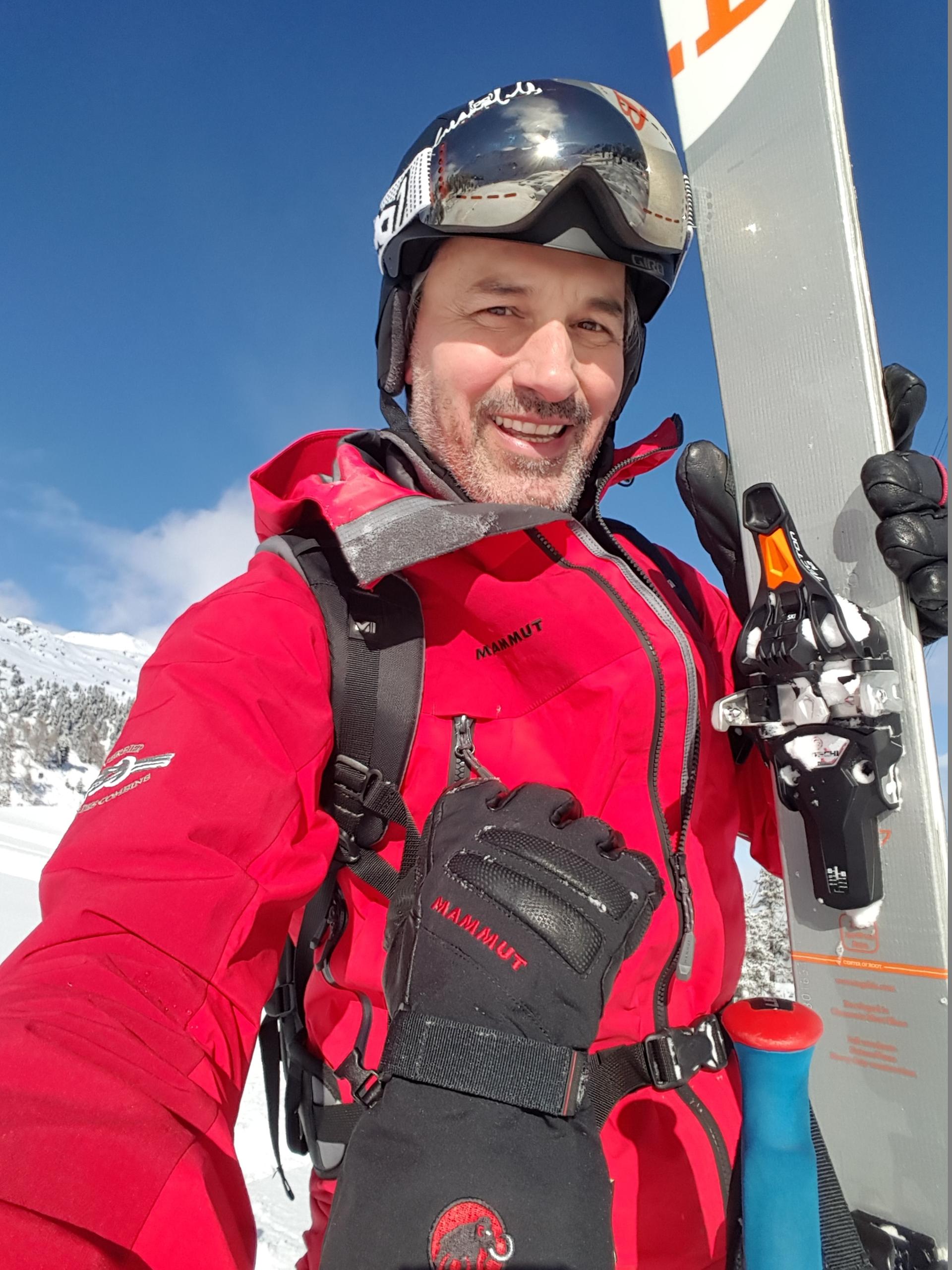 uomo con il casco e degli sci in mano