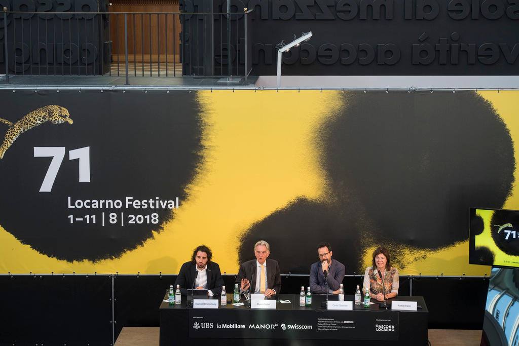 Grosso striscione con la scritta Locarno Festival 71. Si vedono, in basso e in piccolo, 4 persone sedute davanti a microfoni