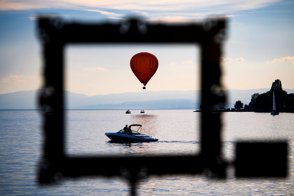 A hot air balloon flies by a motor boat pictured through an Instagram frame