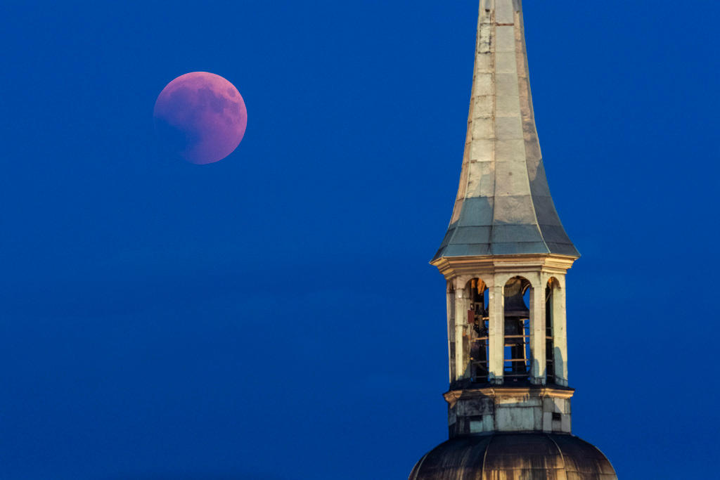 The moon turns red during a total lunar eclipse seen above the Church of Holy-Spirit in Bern