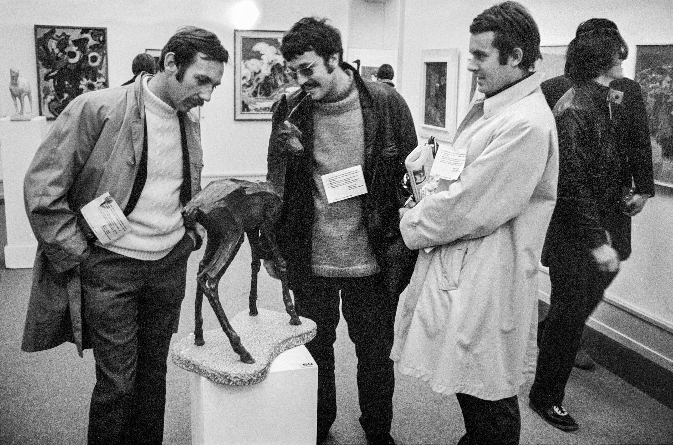 Drei Männer betrachten eine Skulptur