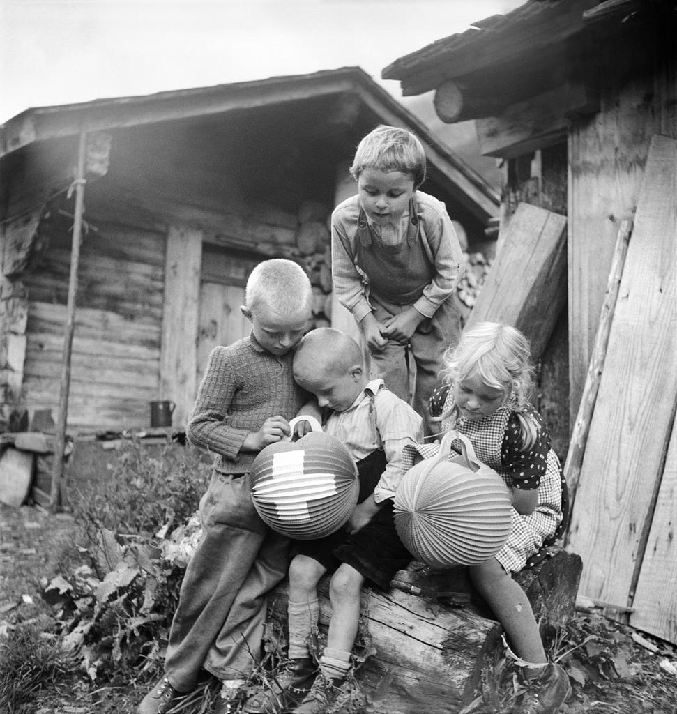 vier kleine Kinder betrachten Lampions vor ihrem Haus