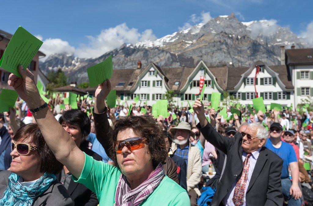 Voters hold up green cards in a vote in canton Glarus.