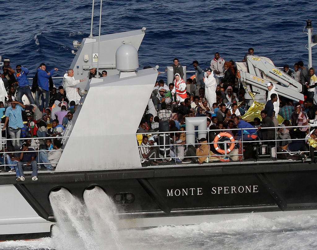 Vista laterale di uno scafo, con la scritta MONTE SPERONE; sul ponte della nave, decine di persone stipate