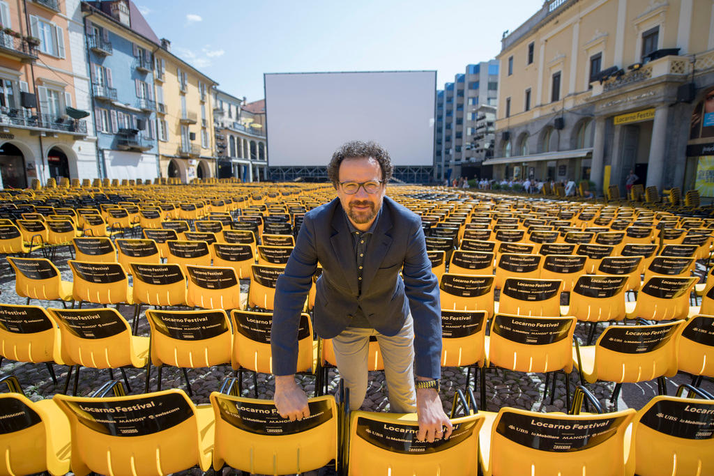 رجل يقف وسط المئات من الكراسي الصفراء المُصففة في الساحة الكبرى لمدينة لوكارنو