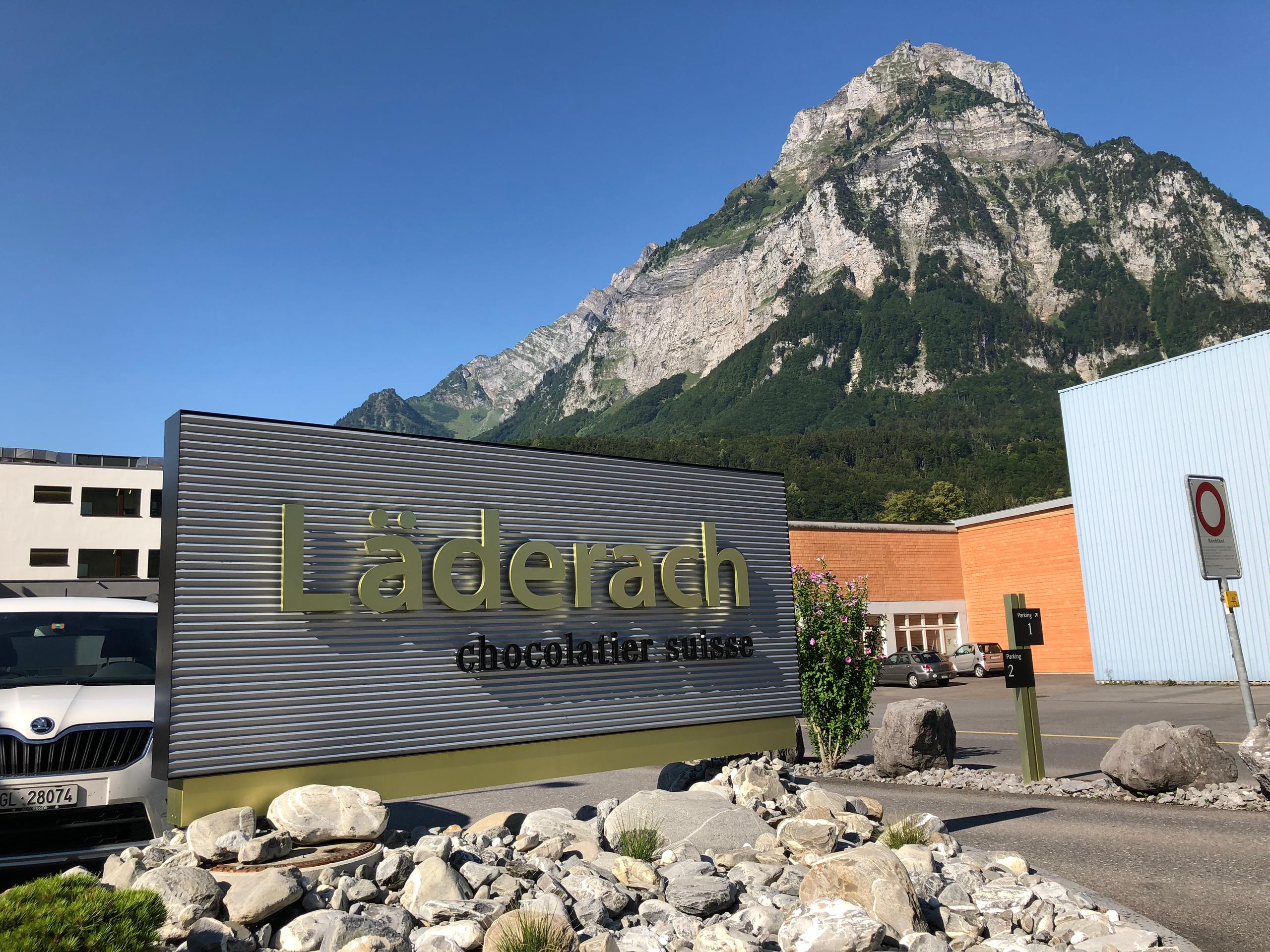 Entrada a una fábrica de Läderach con una montaña al fondo