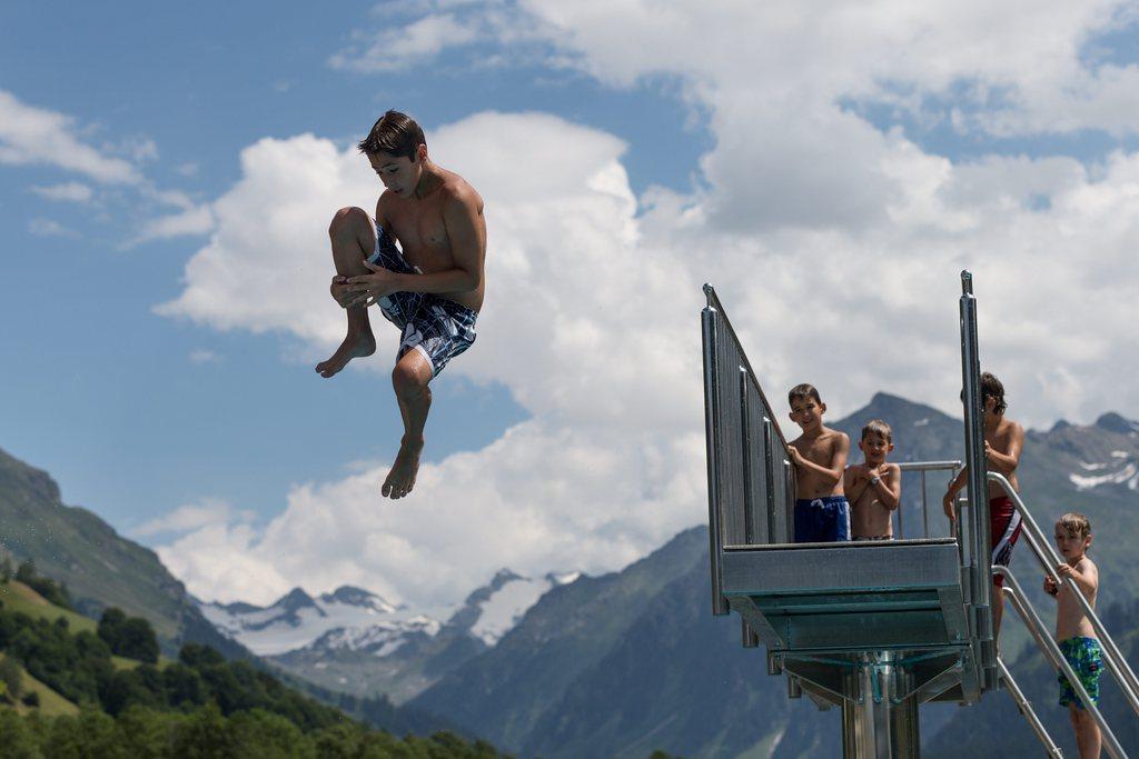 мальчики прыгают в воду с вышки на фоне гор