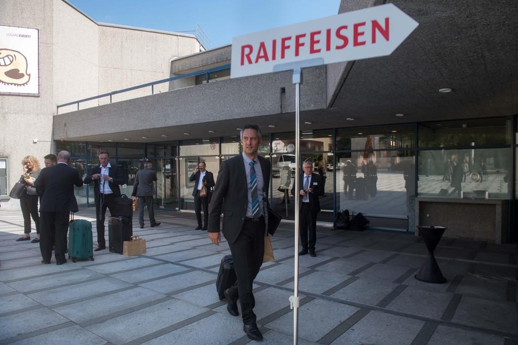 Man in suit and tie walks beside Raiffeisen sign