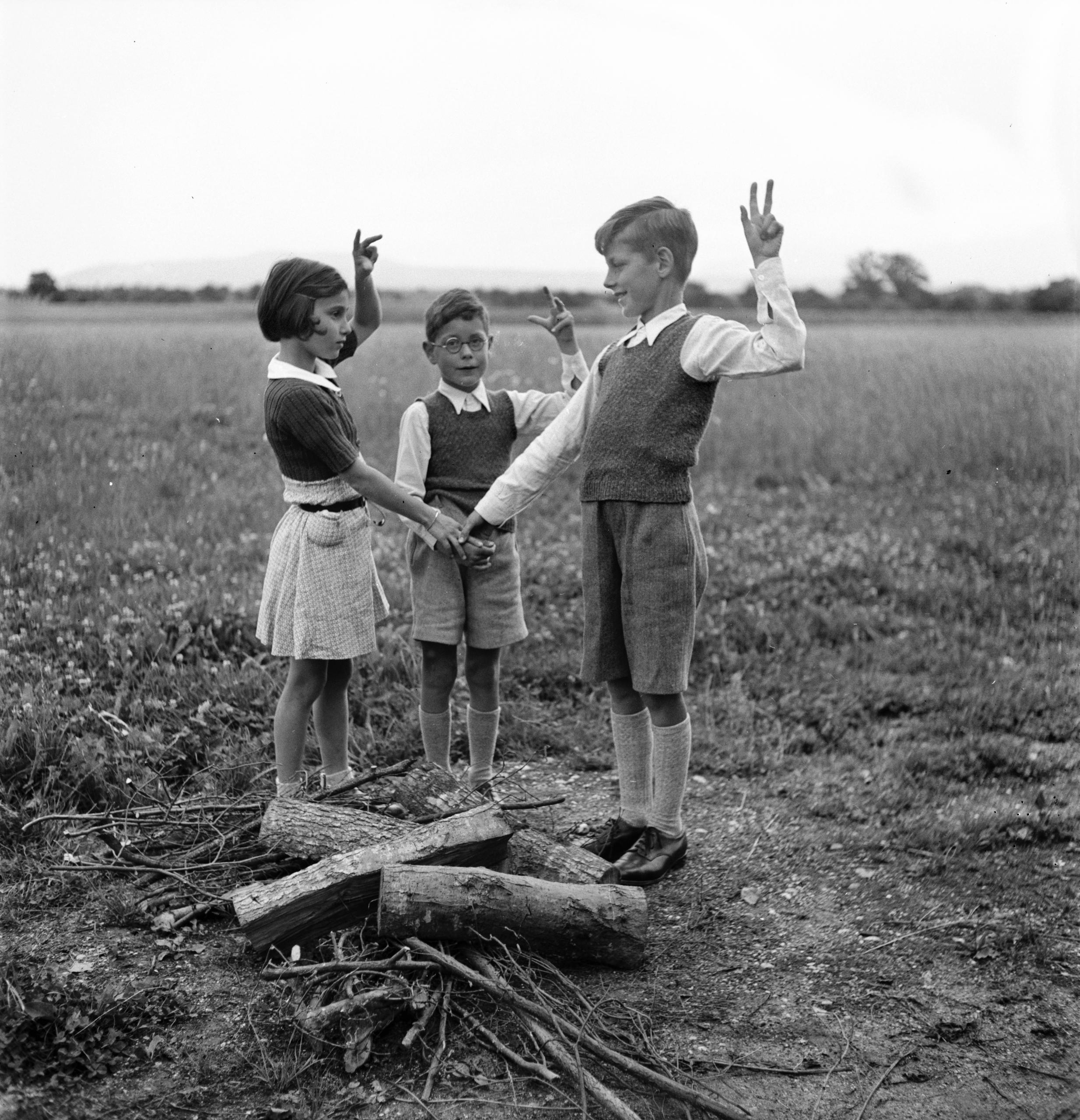 Three children standing by wooden logs making a vow.