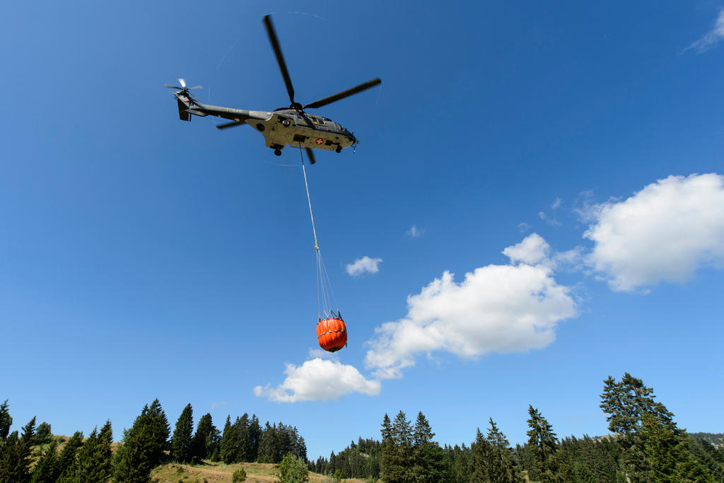 A Swiss army Superpuma Helicopter discharges water over the forest fires near Mesocco in Southern Switzerland