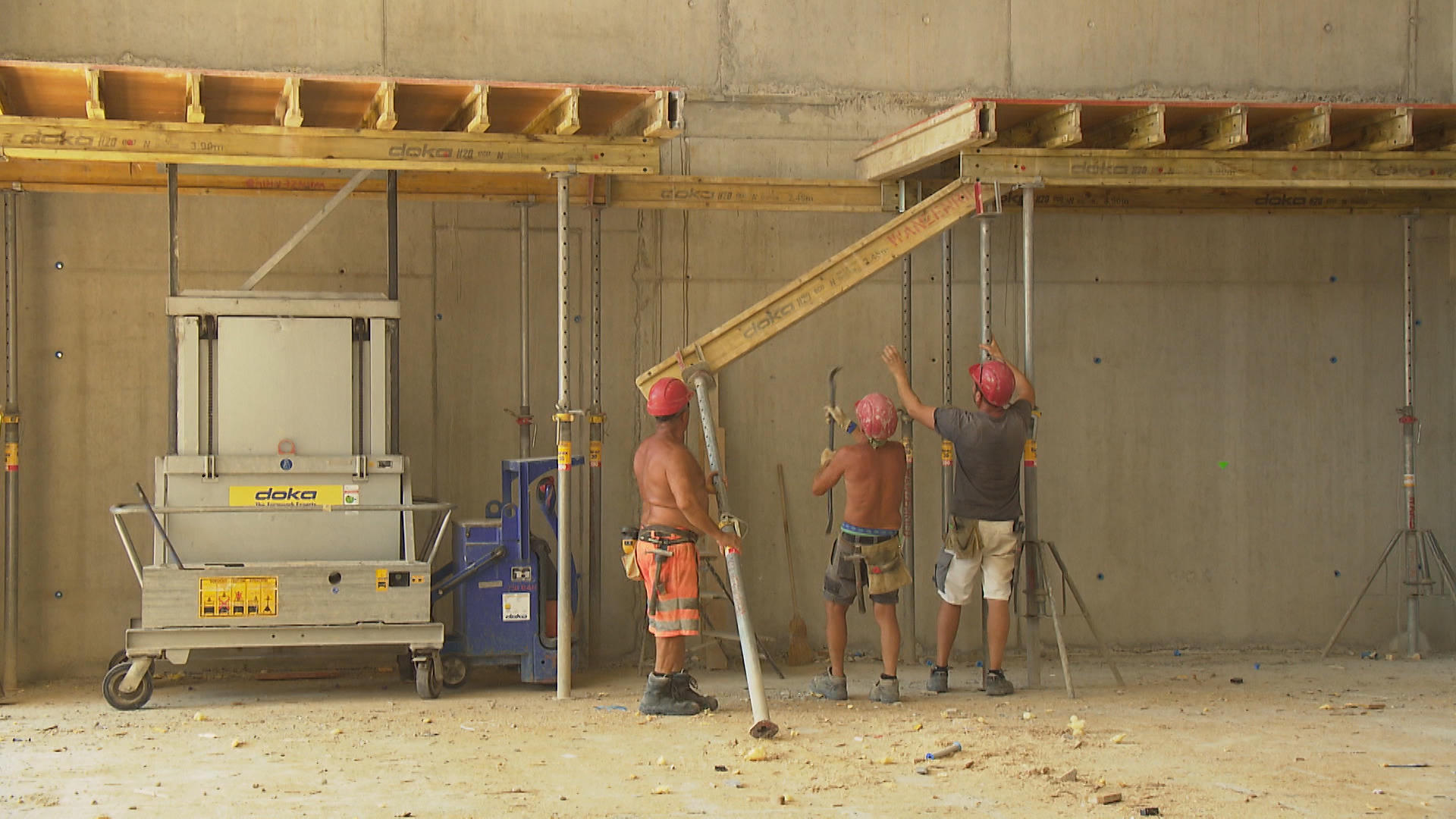 workers inserting a joist in a big room