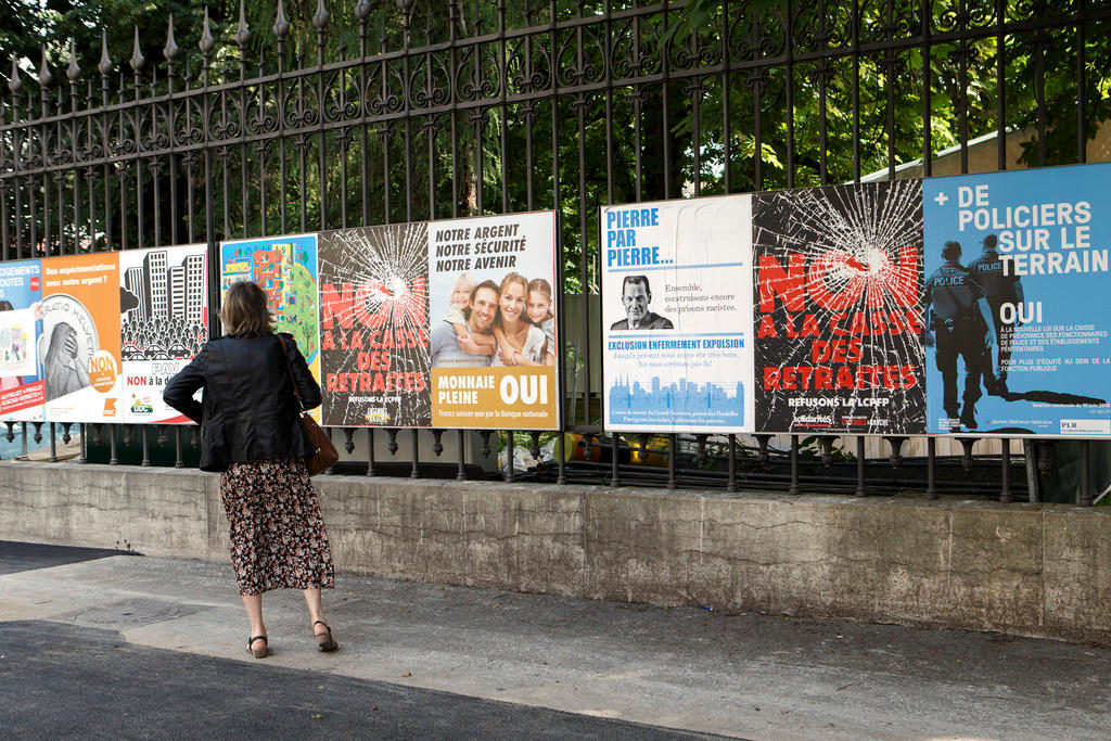Vote campaign posters line a public park fence in Geneva.