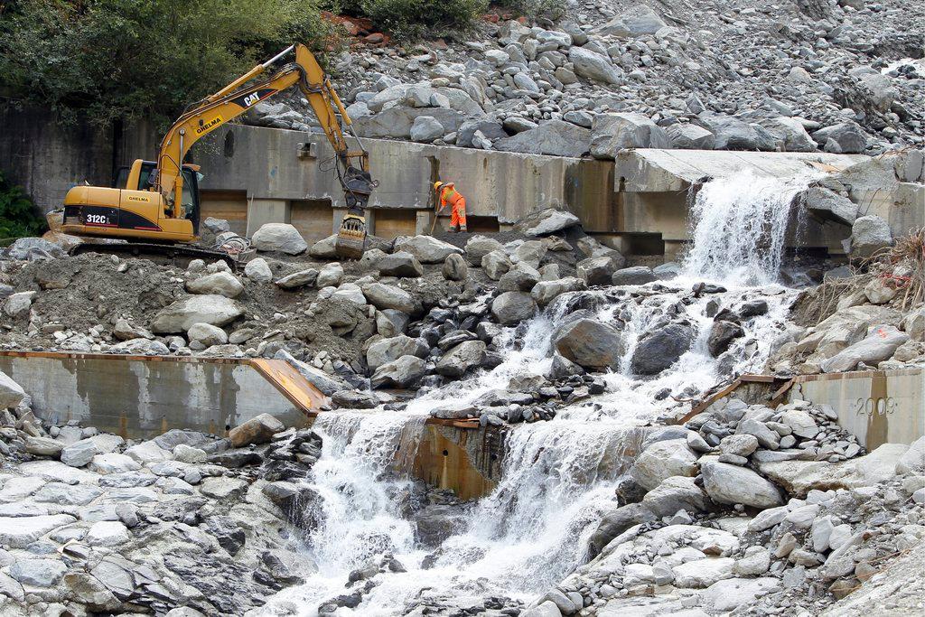 una scavatrice ai bordi rimuove le pietre ai bordi di un torrente